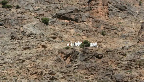 Eine Gruppe von Berber-Algeriern in traditioneller Kleidung wandert auf einem felsigen Hang.